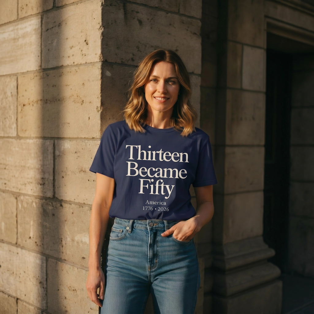 Woman wearing a blue t-shirt with text standing against a stone wall.