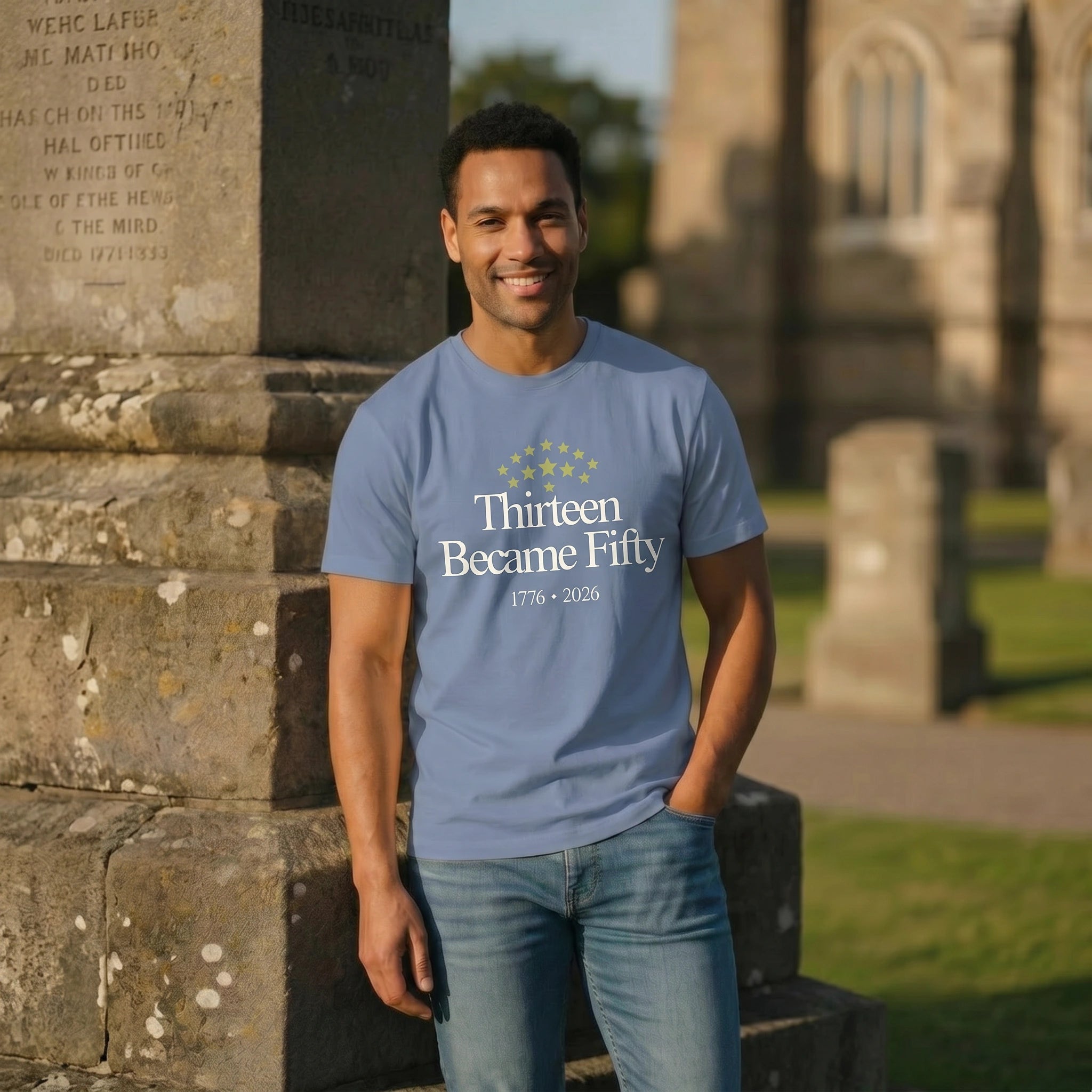 Man wearing a blue t-shirt with text standing in front of a stone monument.